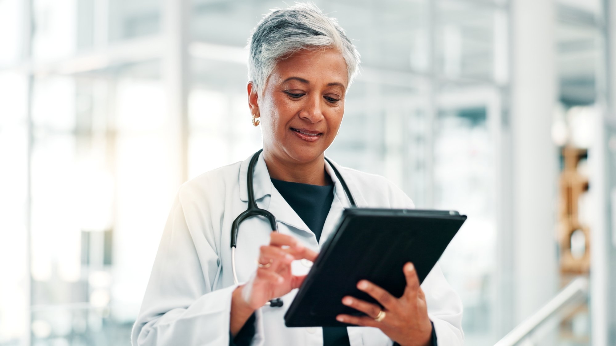 Female doctor reviewing patient data on a tablet, with the help of Hart.