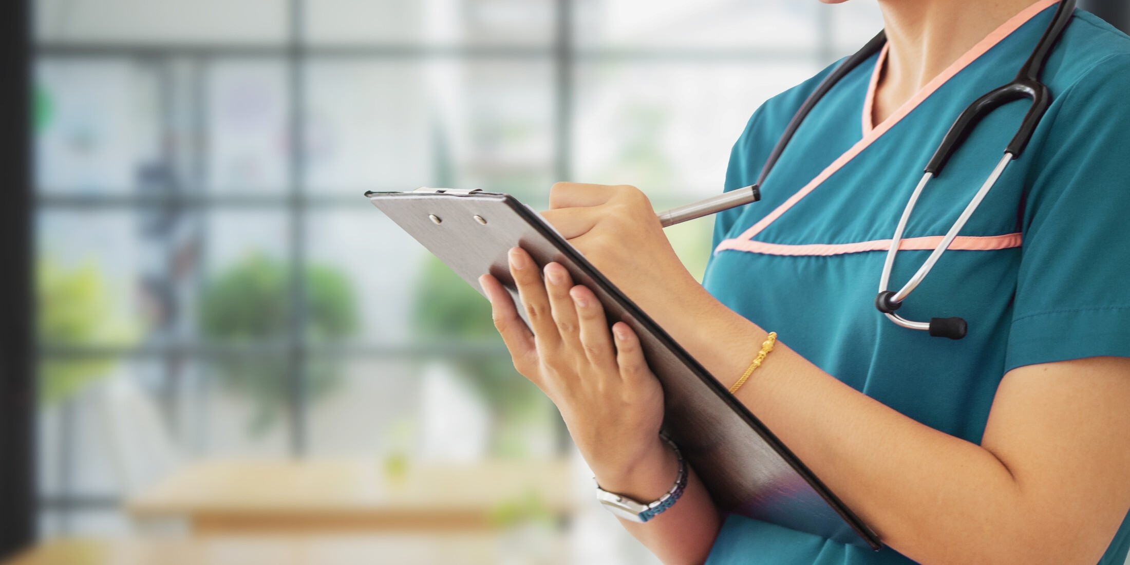 Nurse in scrubs writing on a clipboard, representing the clinical workflows that depend on HL7 data exchange.